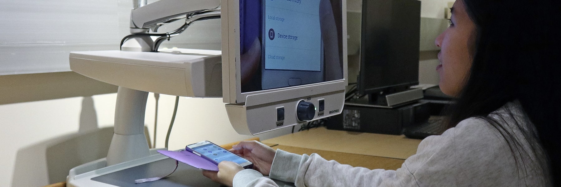 student holding phone scanning with assistive technology equipment