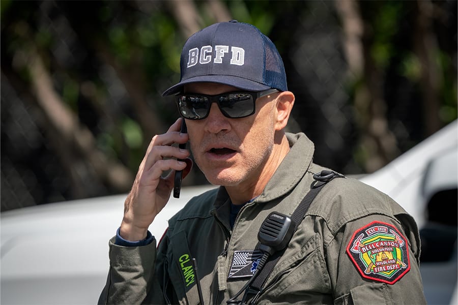 Man fire department baseball hat talks on cellphone.