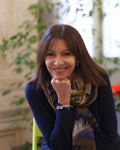 Photo of Anne Hidalgo seated in front of a small green tree.