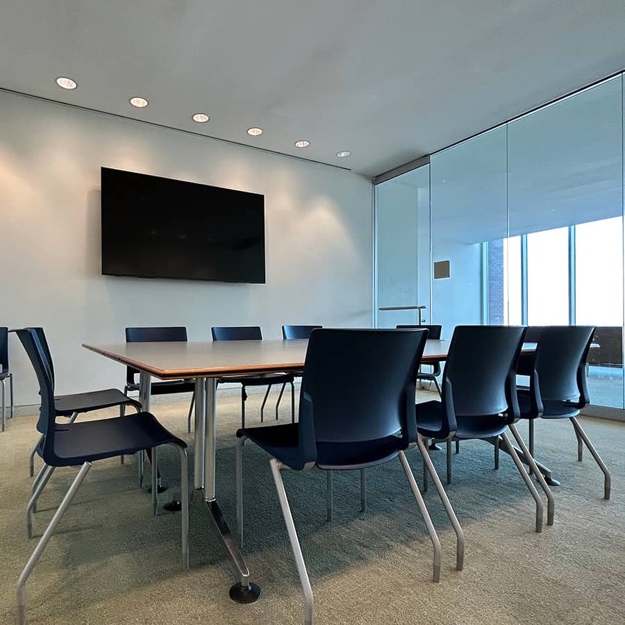 Empty meeting room of table with chairs and TV on the wall.
