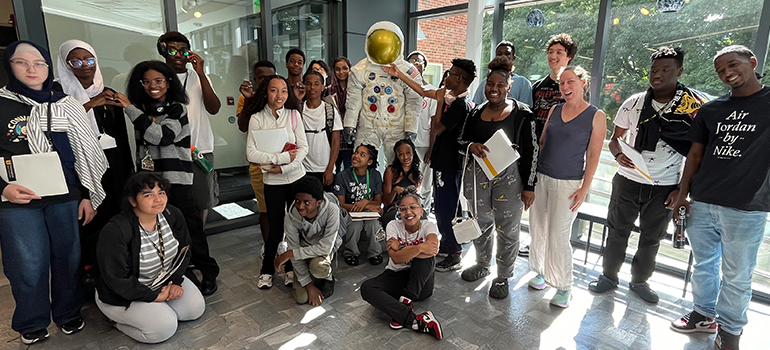 Students and staff with space suit statue